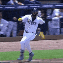 a baseball player wearing a rays jersey is running towards home plate