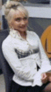 a woman in a white shirt is sitting on a chair