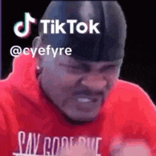 a man in a red shirt is making a funny face while wearing a hat .