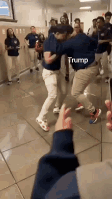 a group of young men are dancing in a hallway while a person holds a cell phone .
