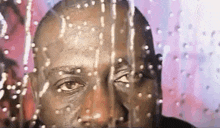 a close up of a man 's face through a window with water drops on it