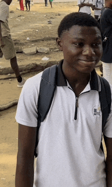 a young man wearing a white shirt with the letter h on the front