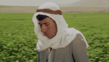 a man in a white turban stands in a green field