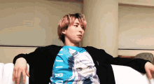 a man with pink hair is sitting on a white couch wearing a blue shirt that says jiro