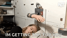 a woman is sleeping in bed with an alarm clock on the wall behind her .