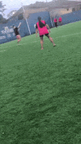 a woman in a pink dress is kicking a soccer ball on a field