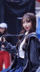 a girl in a school uniform is holding a tie in her hand