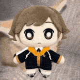 a stuffed doll with a yellow scarf around his neck is sitting on a bed next to a cat