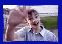 a young boy is waving his hand in front of a white house