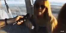 a woman wearing sunglasses is sitting in a car with a man holding a cell phone