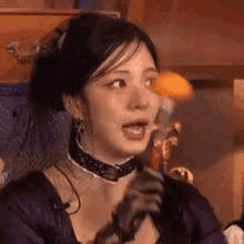 a woman in a purple dress is holding a microphone in her hand and making a funny face .