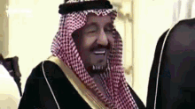 a man in a keffiyeh is smiling while standing next to another man .