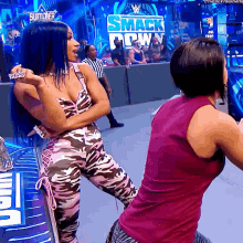 two women are dancing on a stage in front of a smack down sign