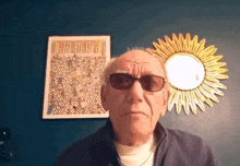 an elderly man wearing sunglasses stands in front of a poster that says " parisian "
