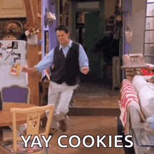 a man is dancing in a living room with the words `` yay cookies '' written in the corner .
