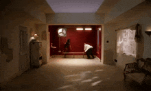 a man standing in a room with a fan on the ceiling