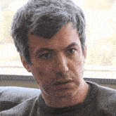 a man with gray hair is looking at the camera with a serious look on his face