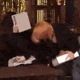 a person covering their face with a piece of paper while another person holds a piece of paper