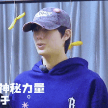 a young man wearing a hat and a blue hoodie
