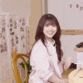 a woman in a pink shirt is sitting in a chair in front of a refrigerator
