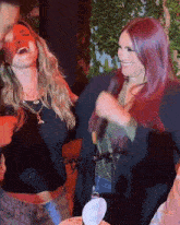 a woman with red hair is laughing next to another woman with blonde hair