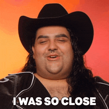 a man with long hair wearing a cowboy hat and a jacket says i was so close