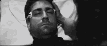 a black and white photo of a man in a hospital bed with a nurse touching his forehead