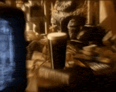 a glass of beer sits on a table in front of a tv screen