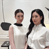 two women standing next to each other with hong kong on the bottom