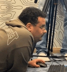 a man wearing a hoodie with the number 7 on the back is using a mouse