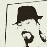 a man with long hair and a beard wearing a hat