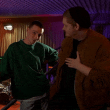 a man in a green sweater is laughing with another man