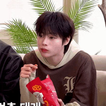 a person wearing a brown shirt with the letter l on it is eating a bag of chips