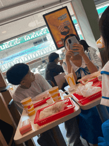 a woman takes a picture of a man eating chicken mayo
