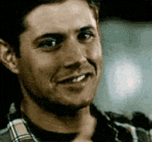 a man in a plaid shirt is smiling and giving a thumbs up