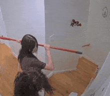a woman is holding a mop while standing on a set of wooden stairs