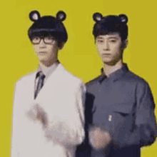 two men are standing next to each other on a yellow background wearing bear hats .