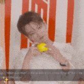 a young man wearing glasses is holding a yellow ball in his hand .