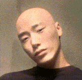 a close up of a bald man 's face with a black shirt on