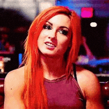 a woman with red hair is wearing a purple tank top and smiling .