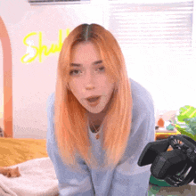 a young woman with red hair is standing in front of a camera in a room .