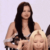 a woman with long black hair is sitting next to another woman with blonde hair