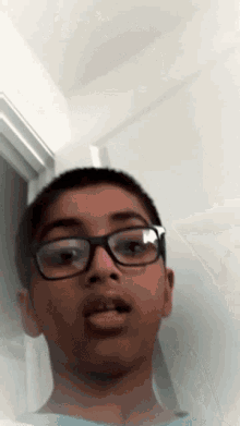 a young boy wearing glasses looks at the camera with his mouth open