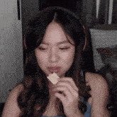 a woman wearing headphones is eating a piece of cheese