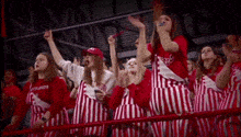 a group of people wearing red and white striped aprons are watching a game