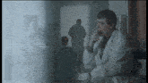 a man in a lab coat is smoking a cigarette in a dark room