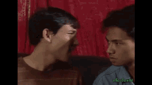 two men are sitting on a couch and laughing together .