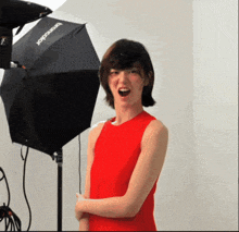 a woman in a red dress stands in front of a black umbrella that says broncolor on it