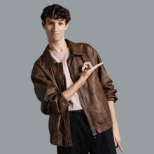 a young man wearing a brown leather jacket and a pink t-shirt