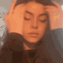 a woman with a nose ring is holding her head .